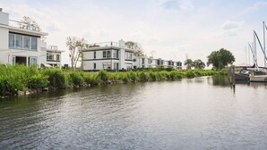 Ein Anwesen am Kanal mit moderner Architektur, einem Steg mit Booten und üppigem Grün.