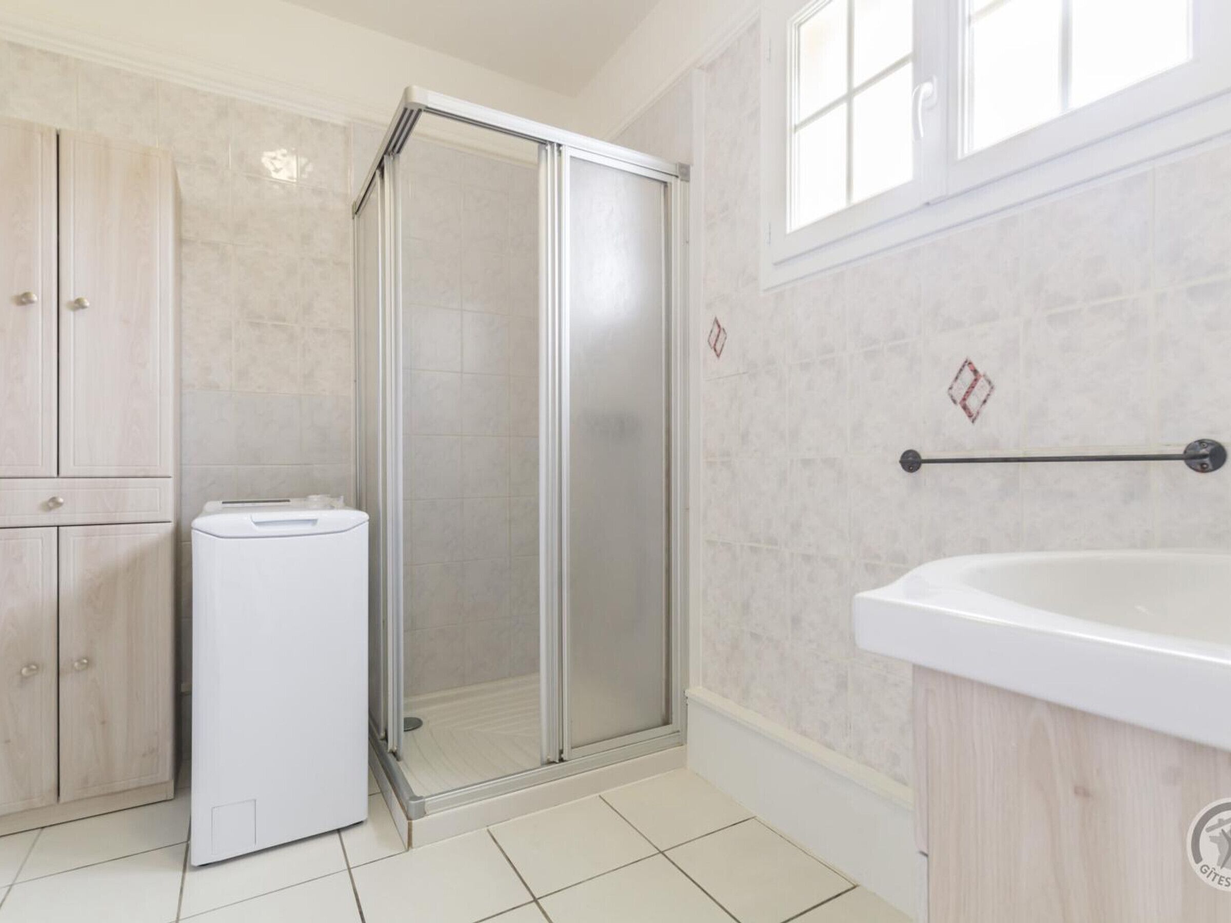 Ein Badezimmer mit Duschkabine, Waschbecken und Schrank.