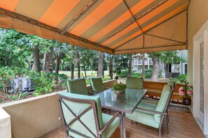 Patio esterno con tavolo e sedie, circondato da un'area coperta con una tenda a righe.