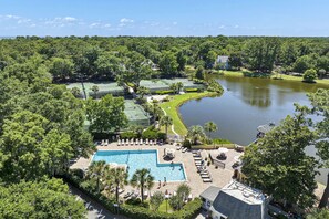 Un resort con piscina, campi da tennis e un lago.