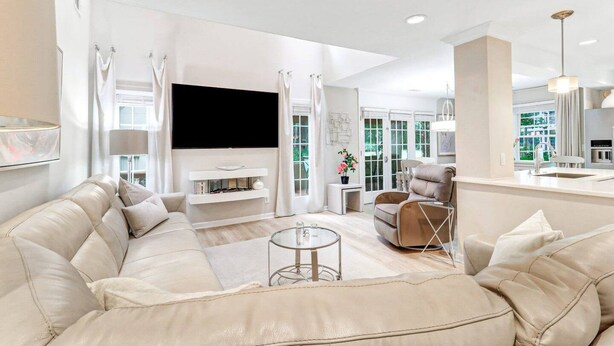 Una sala de estar moderna con un sofá color beige, un televisor de pantalla plana y una mesa de centro de vidrio.