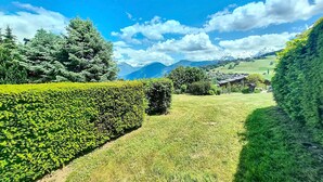 Un jardín cuidado con setos, césped y vistas a montañas en la lejanía.