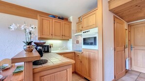 Una cocina compacta con armarios de madera, un microondas, una cafetera y un lavamanos.