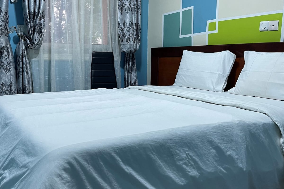 A neatly made bed with white linens in a hotel room.