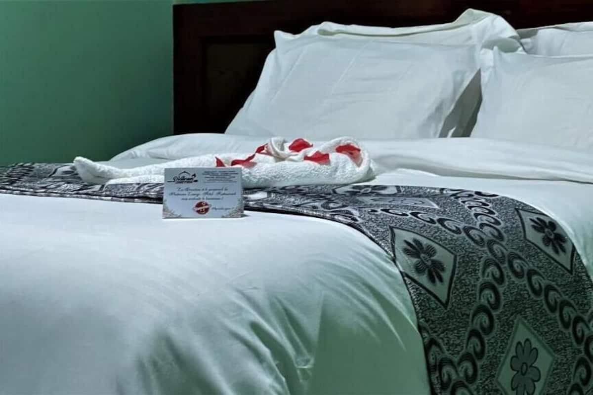 A neatly made bed with white linens and a patterned throw blanket.