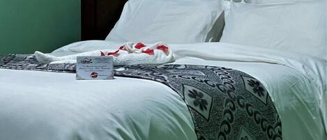 Un lit bien fait, avec des draps blancs et un plaid à motifs.