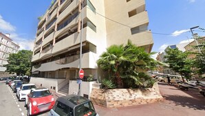 A multi-story building with a parking lot in front. - Le Center avec joli balcon et parking (Cannes)