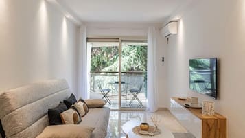 A modern living room with a sofa, a coffee table, and a TV mounted on the wall.