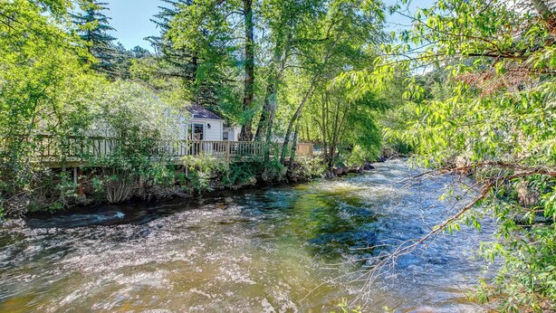 Ein Fluss fließt durch eine bewaldete Landschaft, mit einem kleinen Haus auf Stelzen.