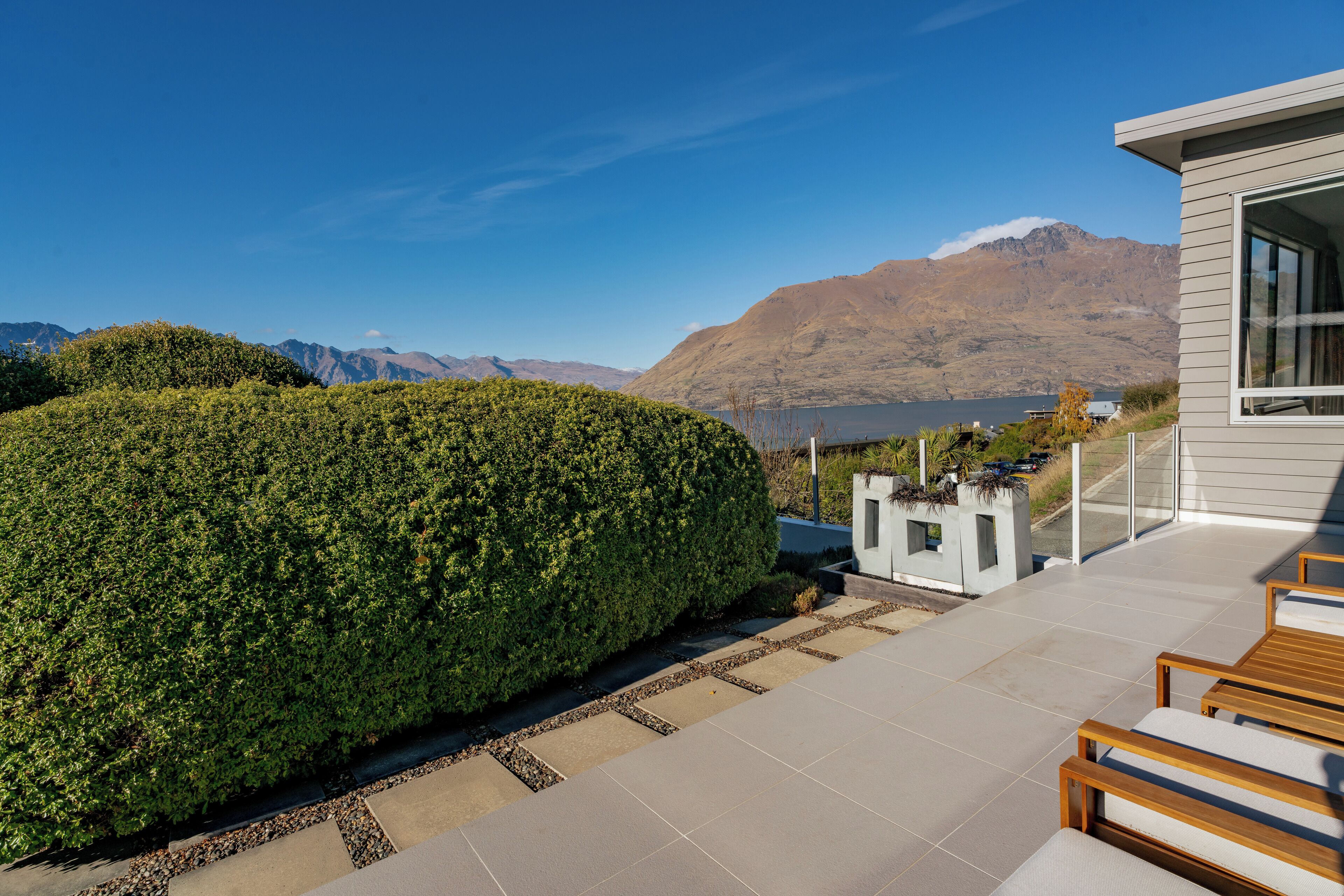 Un espace extérieur moderne, aménagé avec des sièges, offrant une vue sur les montagnes et un lac.