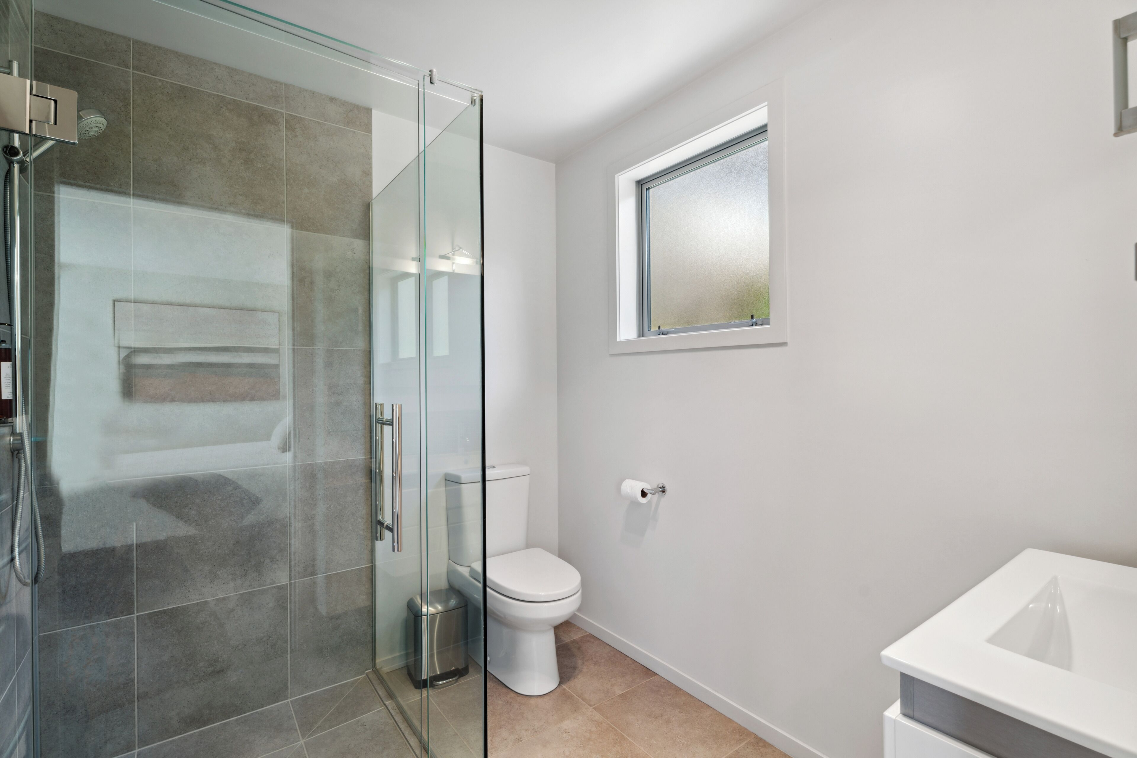 A modern bathroom with a glass shower enclosure, a toilet, and a sink.