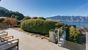 A terrace with outdoor seating, a view of mountains, and a body of water. - Luxury Retreat - Matakauri (Queenstown)