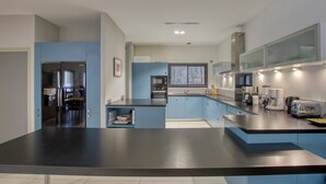 Une cuisine moderne avec des armoires bleues, des appareils en acier inoxydable et un comptoir noir.