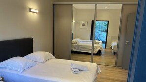 Une chambre d’hôtel avec deux lits, une porte coulissante donnant sur un balcon et une petite table de chevet.