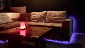 A modern living room with a sofa, a coffee table, and a wall-mounted light fixture. - MBAR HOSTEL HAAD RIN  (Ko Pha-ngan)