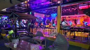 A vibrant bar area with neon lights, a DJ booth, and seating arrangements. - MBAR HOSTEL HAAD RIN  (Ko Pha-ngan)