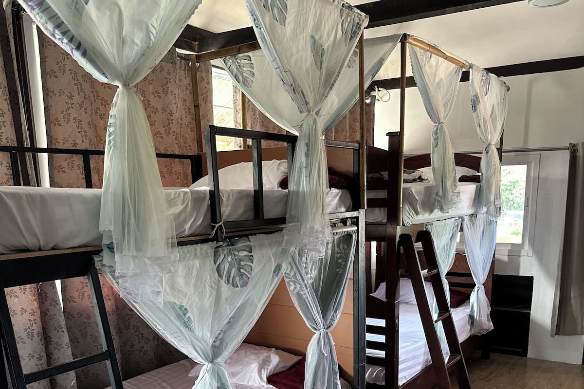 A dormitory room with bunk beds, each covered with mosquito netting.