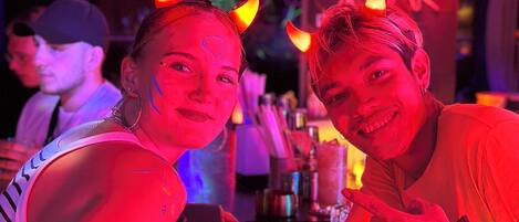 Two people at a bar with a neon sign in the background.