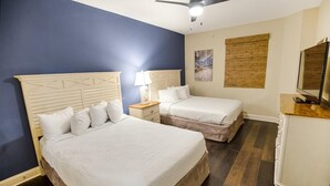 A hotel room with two beds, a nightstand, a dresser, and a ceiling fan.