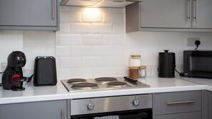 Een keuken met een ingebouwde kookplaat, een koffiezetapparaat, een magnetron en kasten.