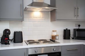 A kitchen with a built-in stove, a coffee maker, a microwave, and cabinets.