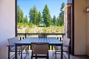 A balcony with a table and chairs, overlooking a forested area. - Virolet | Includes Two 1-Day Lift Tickets (Tamarack)