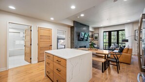 A modern kitchen with a marble island, wooden cabinets, and a dining area with a sofa and table. - Bluebird Bunkhouse|Includes Two 1-Day Lift Tickets (Tamarack)