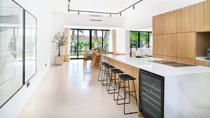 A modern kitchen with a large island, bar stools, and a view of the outdoors. - Villa Peman Marbella Luxory Contemporany 5 Double Rooms Villa Close to the Beach (Marbella)