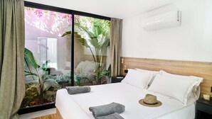 A neatly made bed with white linens, a wooden headboard, and a small nightstand with a candle. - Villa Peman Marbella Luxory Contemporany 5 Double Rooms Villa Close to the Beach (Marbella)