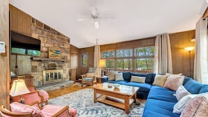 A cozy living room with a stone fireplace, a blue sofa, and a wooden coffee table.