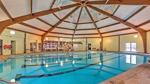 A large indoor swimming pool with clear lanes, wooden beams, and a high ceiling.