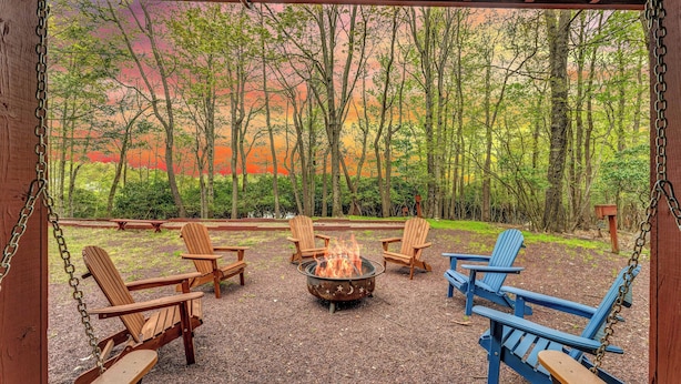A covered outdoor seating area with Adirondack chairs and a fire pit.