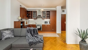 Un apartamento moderno con un sofá gris, muebles de madera, un microondas y una planta en maceta.