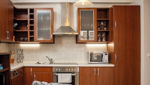 Una cocina moderna con armarios de madera, un lavamanos de acero inoxidable, un microondas y un horno.