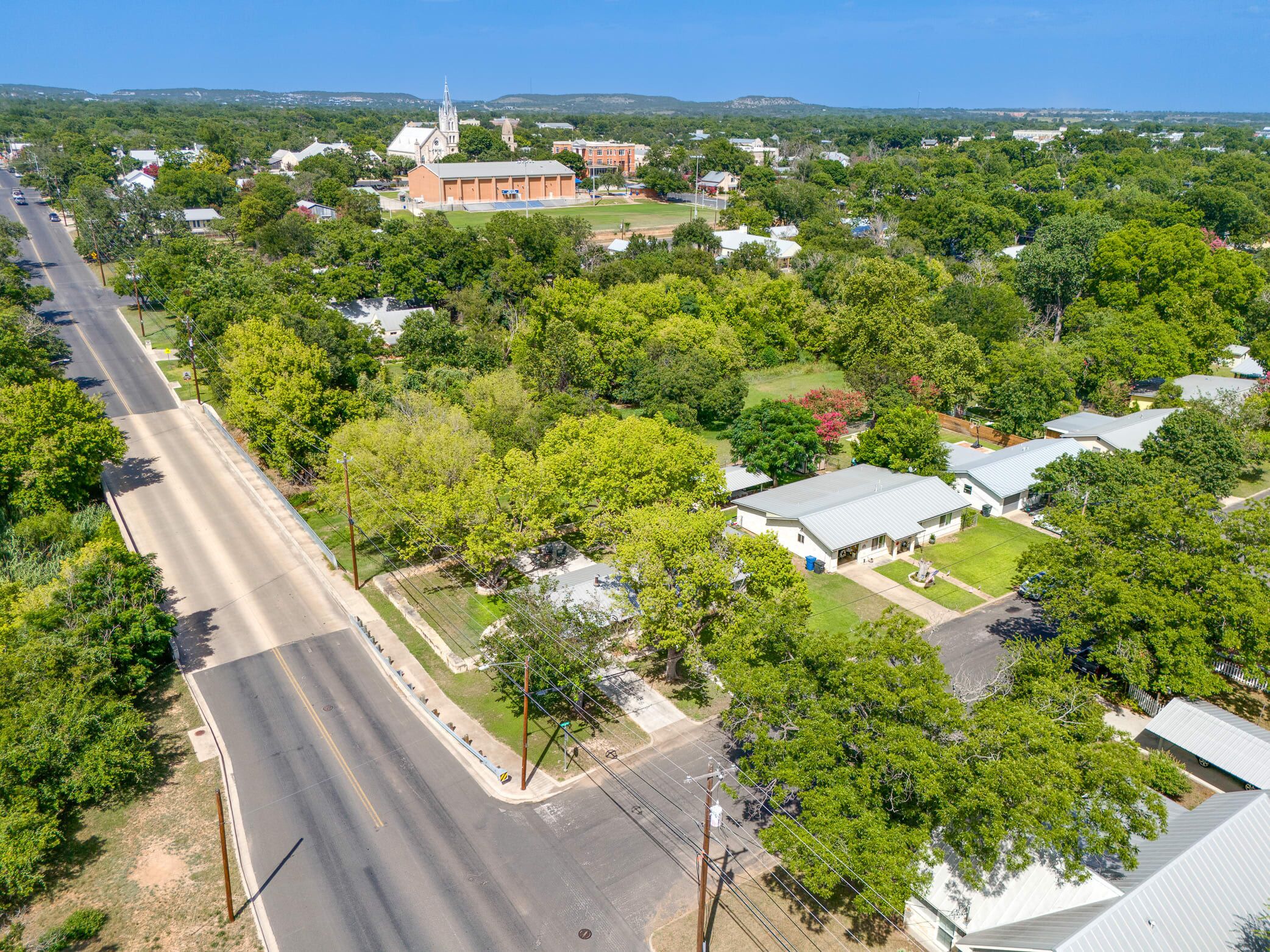 An aerial view of a residential area with houses, a church, and a road.