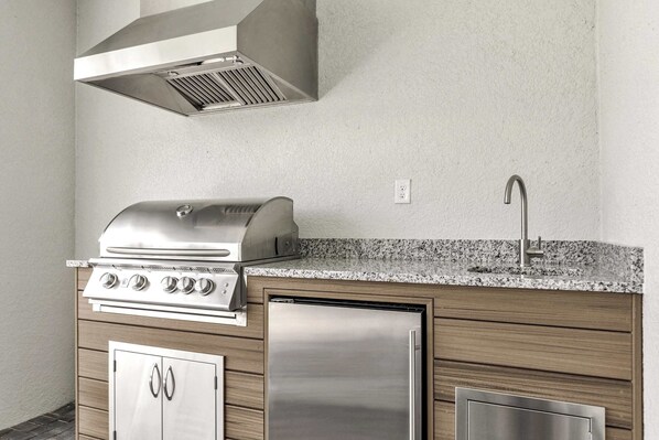Una cocina compacta con estufa a gas integrada, refrigerador de acero inoxidable y encimera de granito.