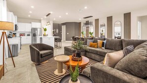Una sala de estar moderna con sofá, sillón, mesa de centro y comedor con mesa y sillas.