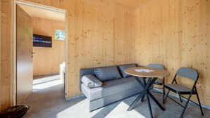 Un interior moderno con pared de madera, un sofá gris, una mesa redonda y una sola silla.