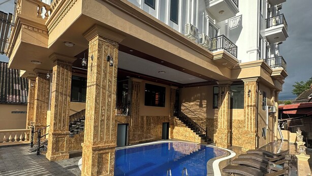 Un immeuble luxueux doté d’une piscine, d’un espace extérieur aménagé et de plusieurs balcons.