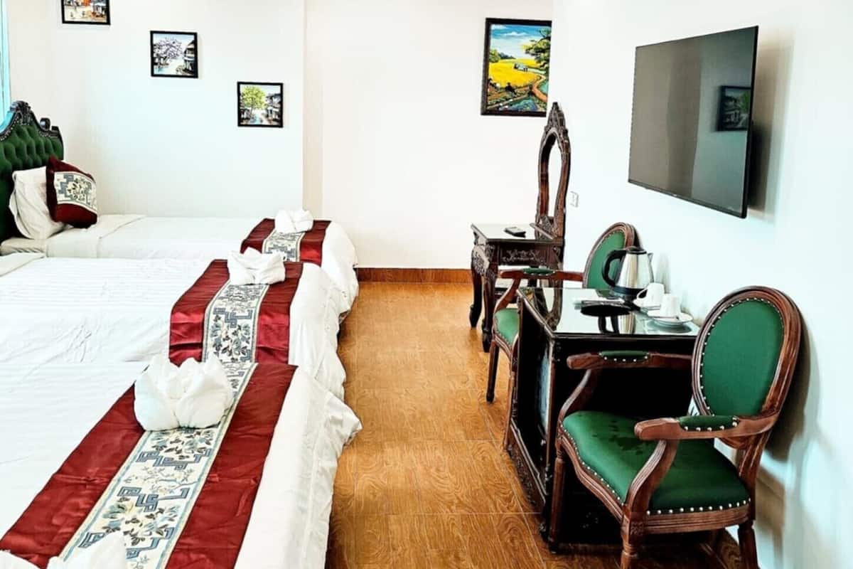 Une chambre d’hôtel avec un grand lit, un bureau avec une chaise, une télévision et des tableaux encadrés au mur.
