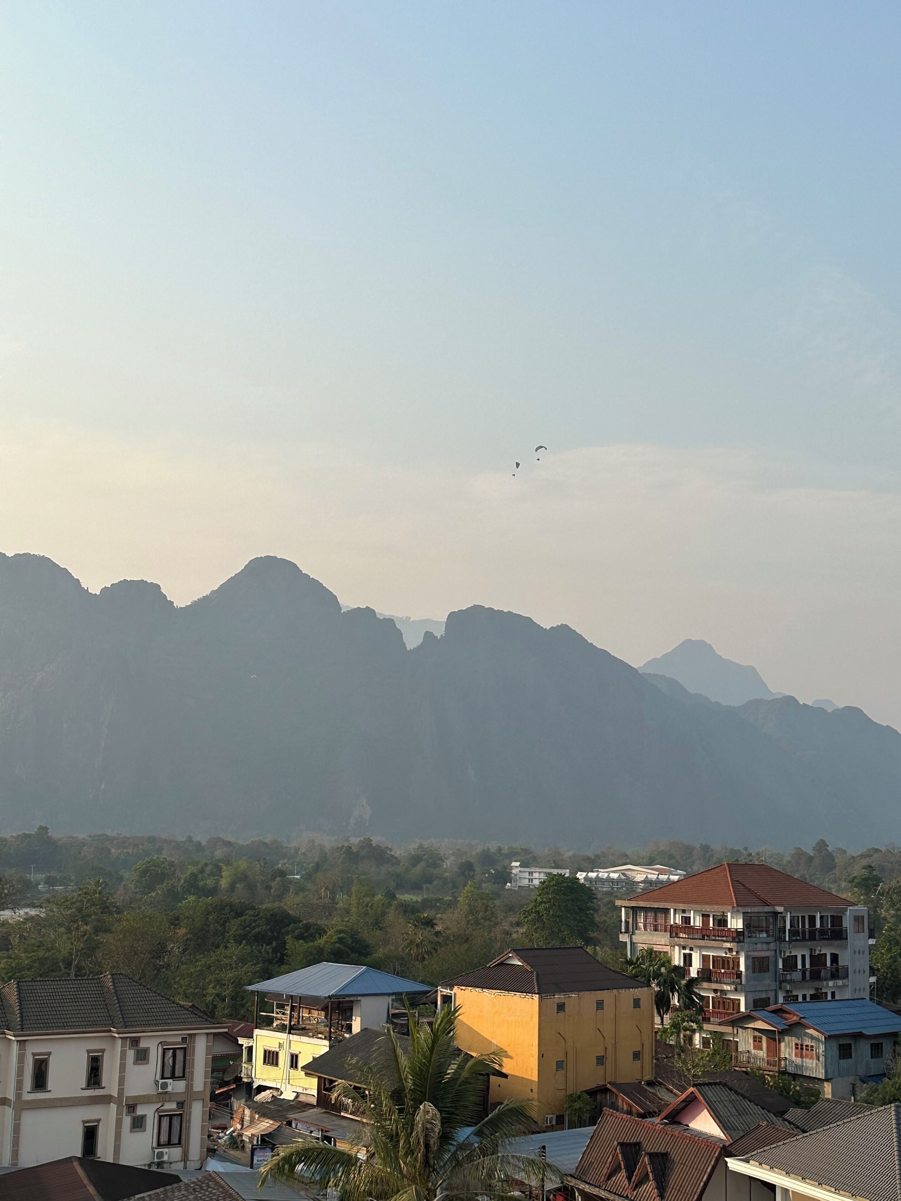 A residential area with multi-story buildings, some with balconies, and a mountainous backdrop.