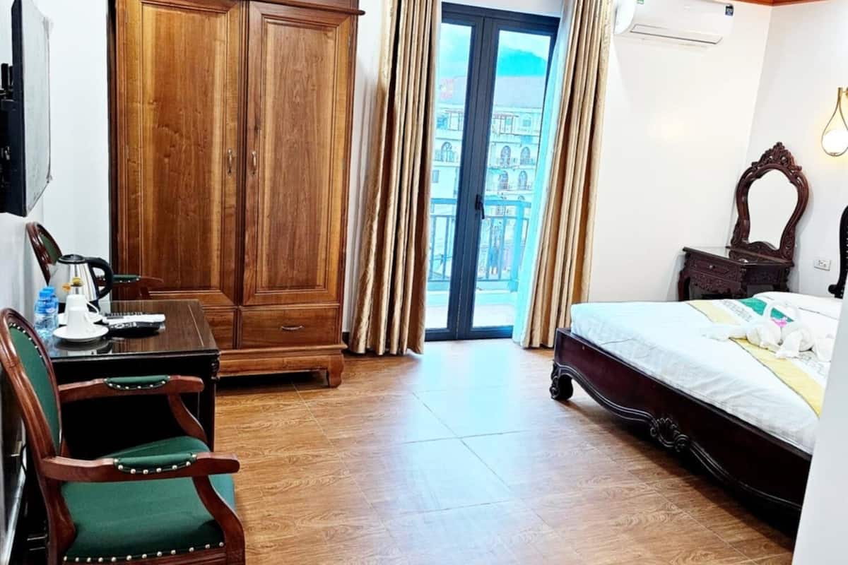 Une chambre d’hôtel avec une armoire en bois, un bureau avec une chaise, un lit et un ventilateur de plafond.