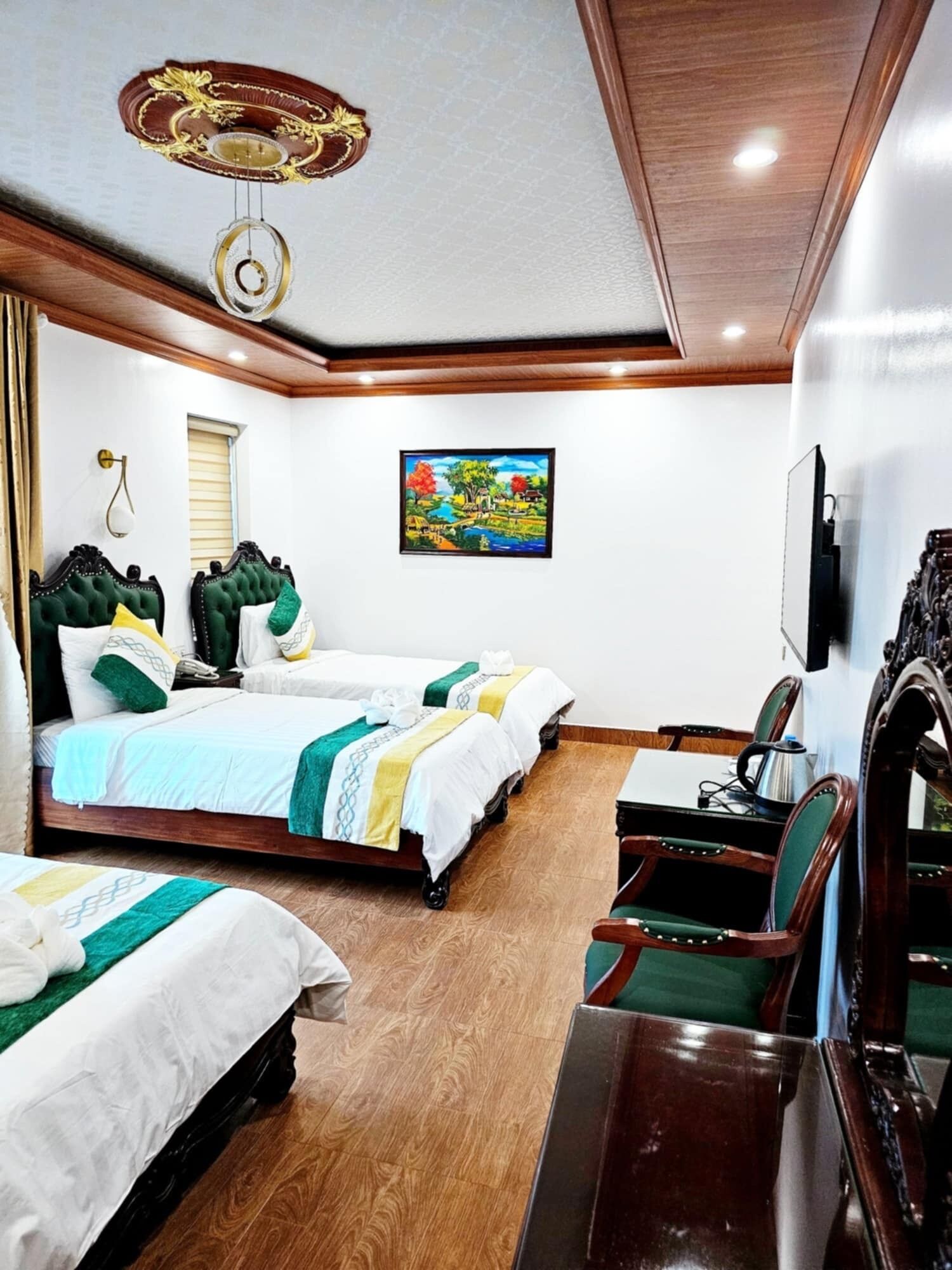 A hotel room with two beds, a wooden ceiling, a painting, a TV, and a wooden desk.