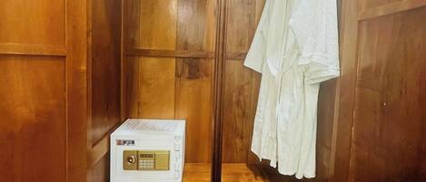 Un armario de madera con un espejo, una bata blanca colgada y un pequeño electrodoméstico en el estante.