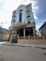 Un hotel de estilo arquitectónico clásico, con una entrada central que incluye una escalera y un balcón con barandillas ornamentadas.