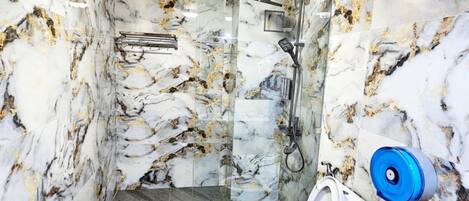 Een badkamer met marmeren wanden, een houten plafond, een douche en een toilet.