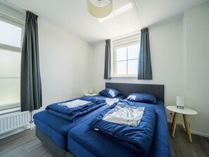 A bedroom with a large bed, two bedside tables, a window with curtains, and a ceiling light. - Holiday Home With Sauna Near Amsterdam (Uitdam)