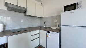 Ett modernt kök med vita skåp, en mikrovågsugn, en diskmaskin och en diskho.
