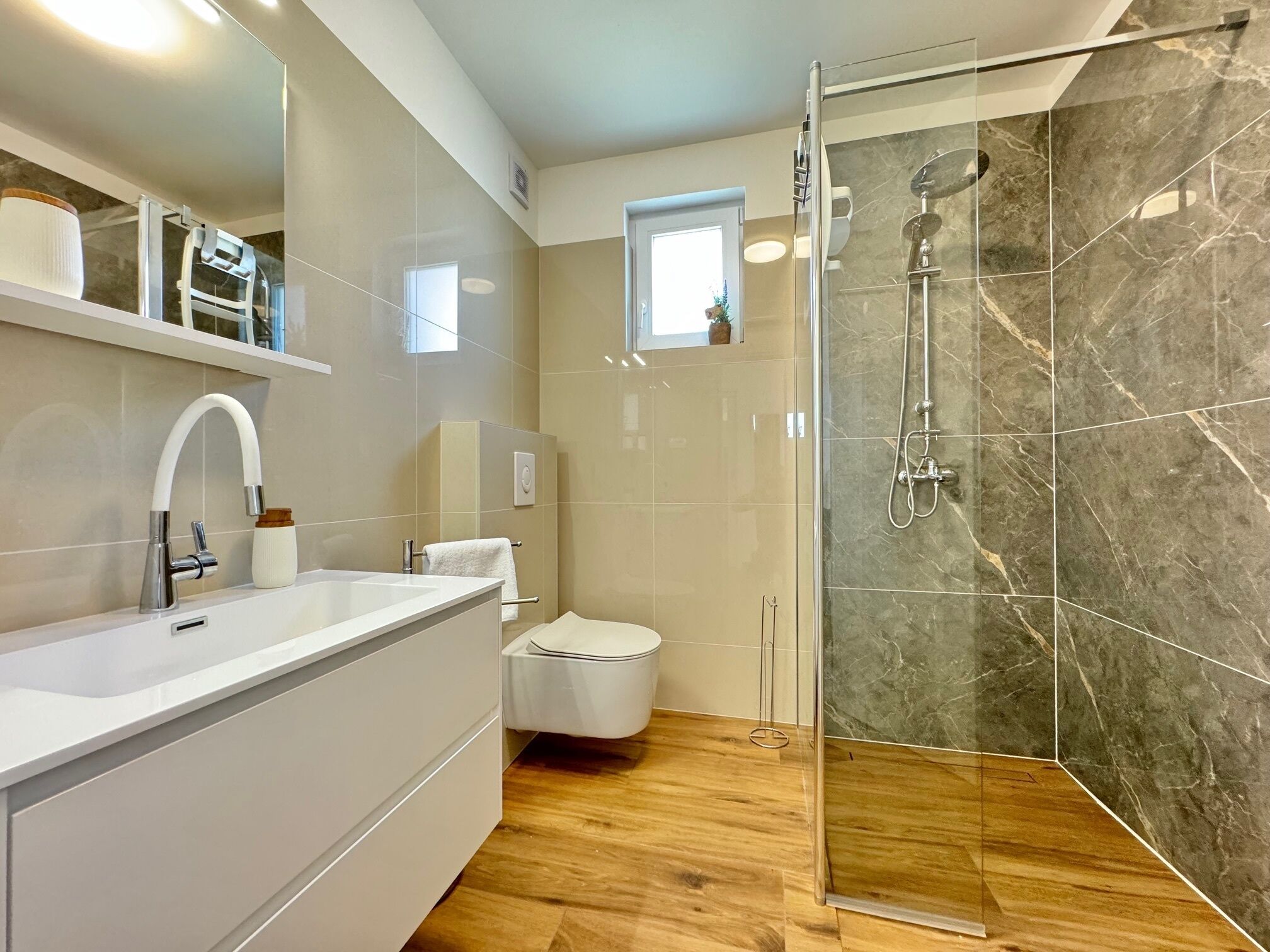 A modern bathroom with a glass-enclosed shower, a white sink, and a toilet.