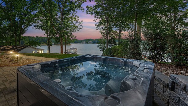 Un jacuzzi con vista a un lago y árboles al atardecer.